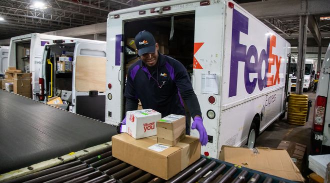 An employee sorts packages on a conveyor belt at a FedEx facility